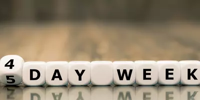 Würfel mit Buchstaben symbolisieren: Die 4-Tage-Woche im Vergleich zu einer 5-Tage-Woche.