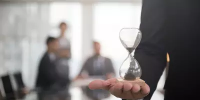 Person die eine Sanduhr in der Hand hält