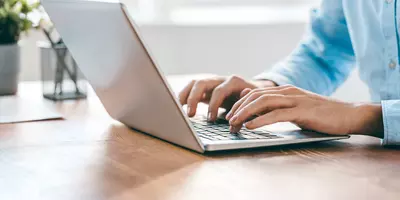 Effektive Kurzbewerbung am Laptop: Ein engagierter Mann tippt konzentriert an seinem Laptop auf einem gut organisierten Schreibtisch.