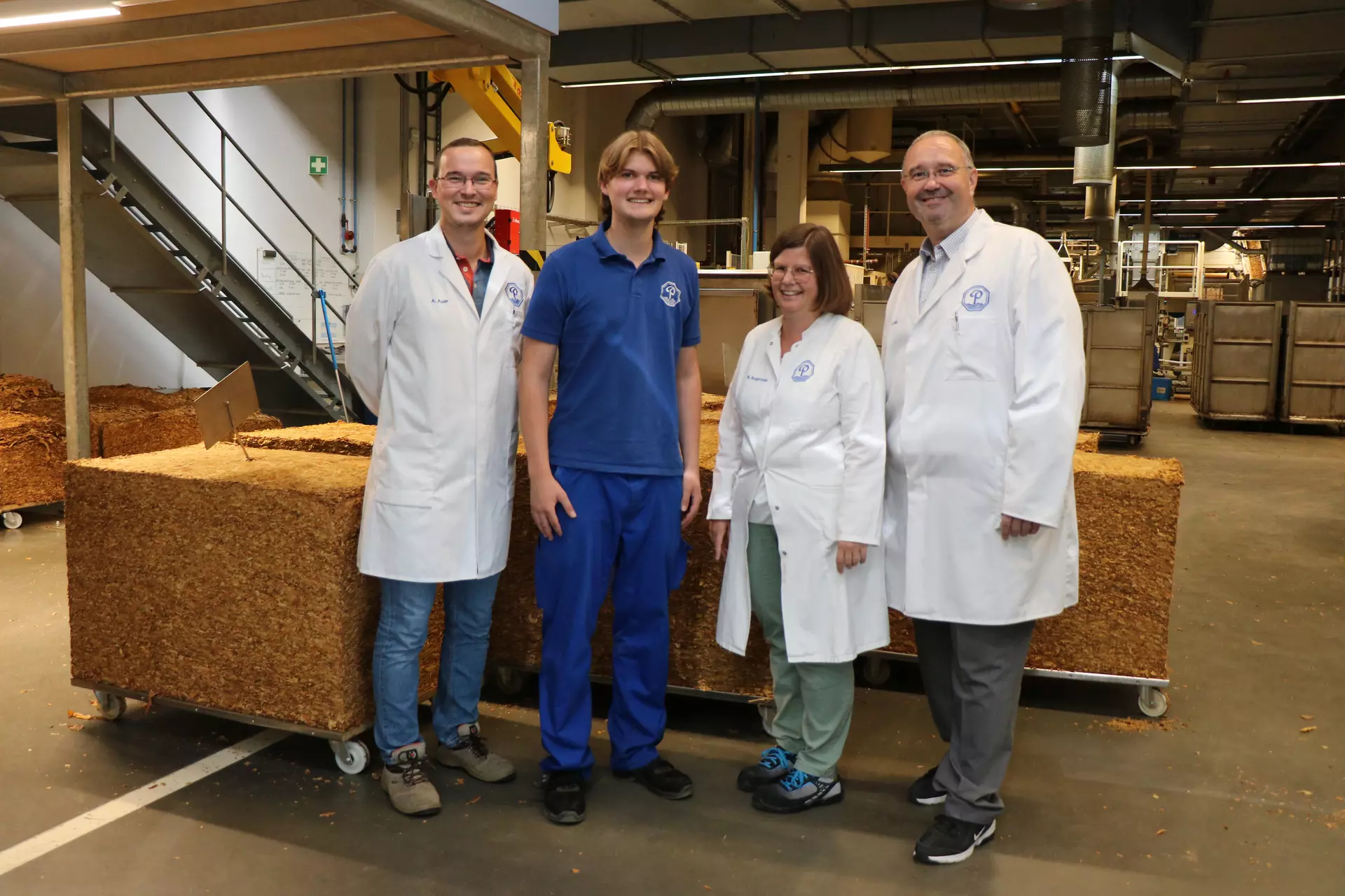 Andreas Auer, Tim Glöde, Michaela Angermair und Alexander Dalli (v. l.) stehen vor den Ballen mit den verschiedenen Tabaksorten, aus denen die Produkte hergestellt werden. Foto: Sandra Schörghuber