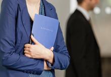 Traditionelle Bewerbungsverfahren: Eine Frau hält ihr Bewerbungsmappe in der Hand - Kurzbewerbungen können hingegen komplett online eingereicht werden.